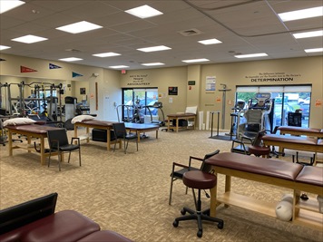 An empty gym with several therapy tables and equipment.