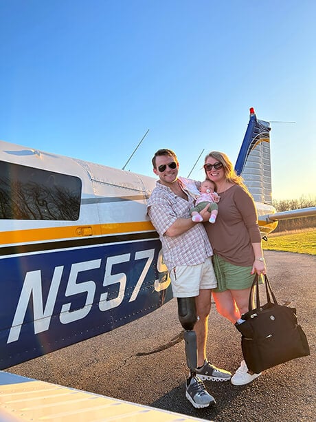 A man, with an artificial leg, and his wife, standing next to an airplane.