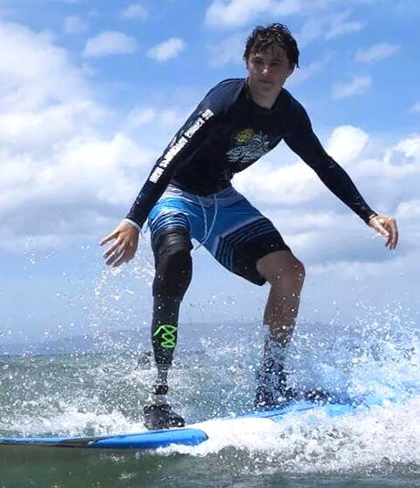 A patient with an artificial leg, surfing in the ocean.