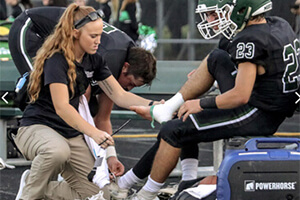 An athletic trainer wrapping a football player's foot