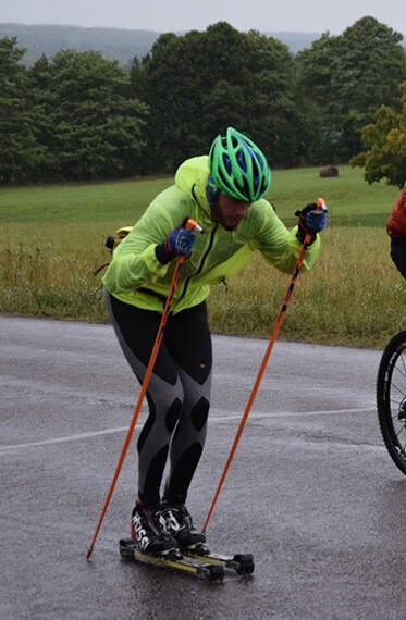 Action shot of Tom outside rollerskiing with a green a jacket and hel,met on