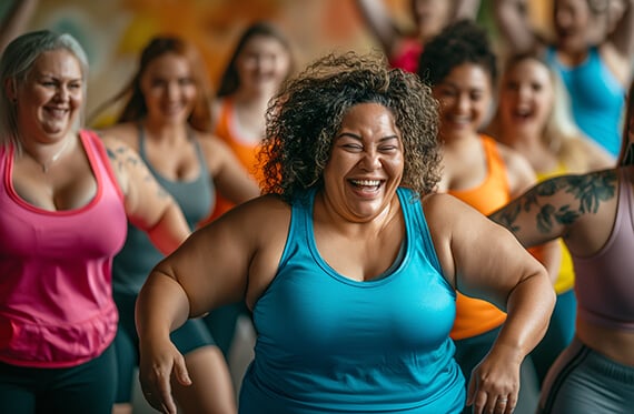 A group of women smiling during a fitness dance class